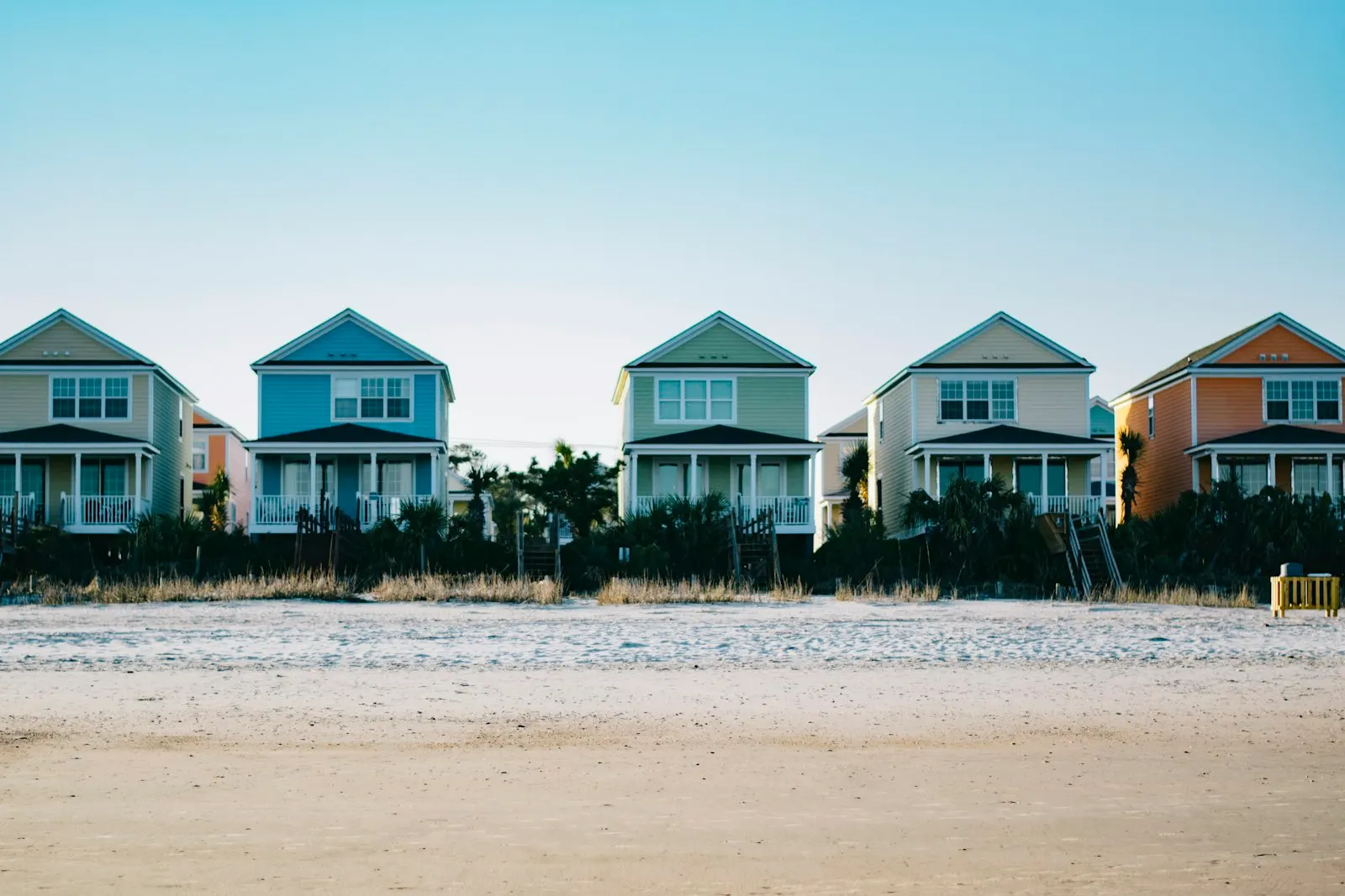 A row of five colourful two-storey holiday homes in a neat line.