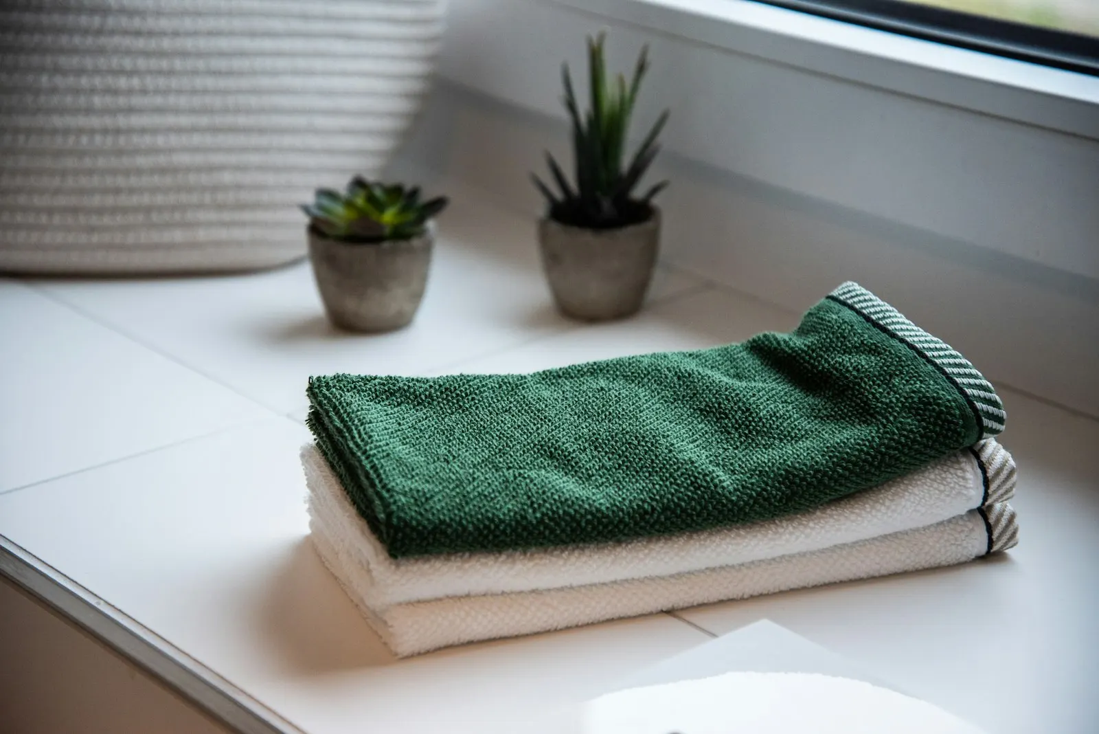 Folded towels on a shelf next to small potted plants.