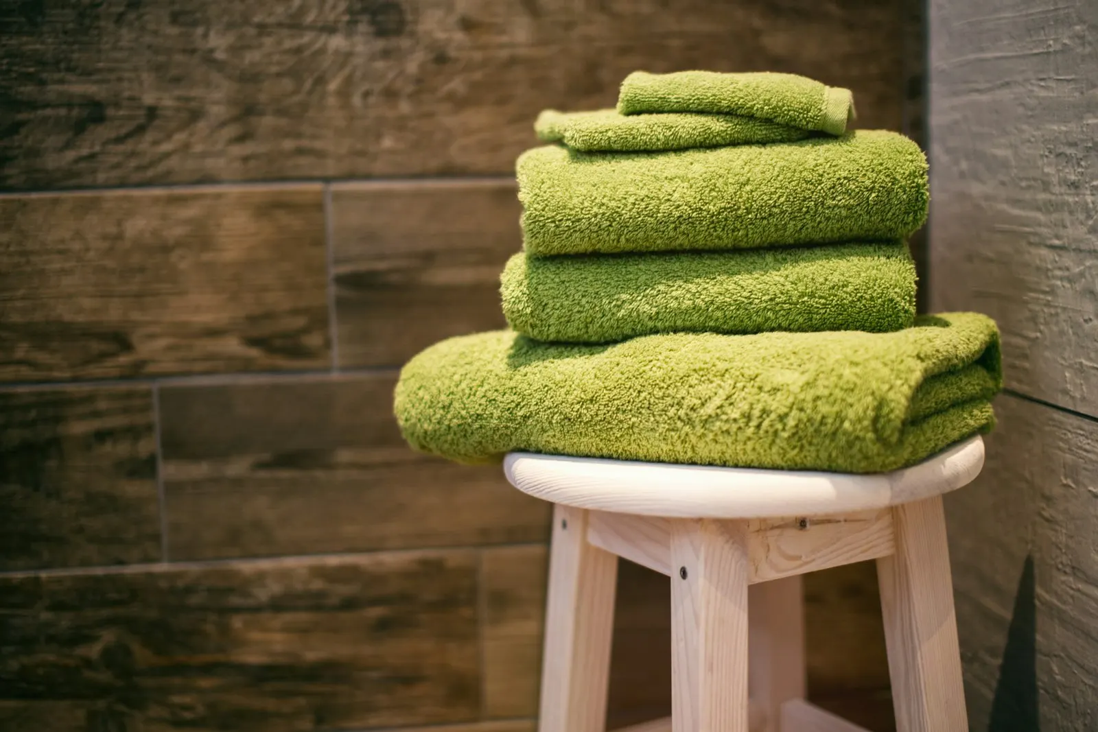 A neat stack of four green towels.