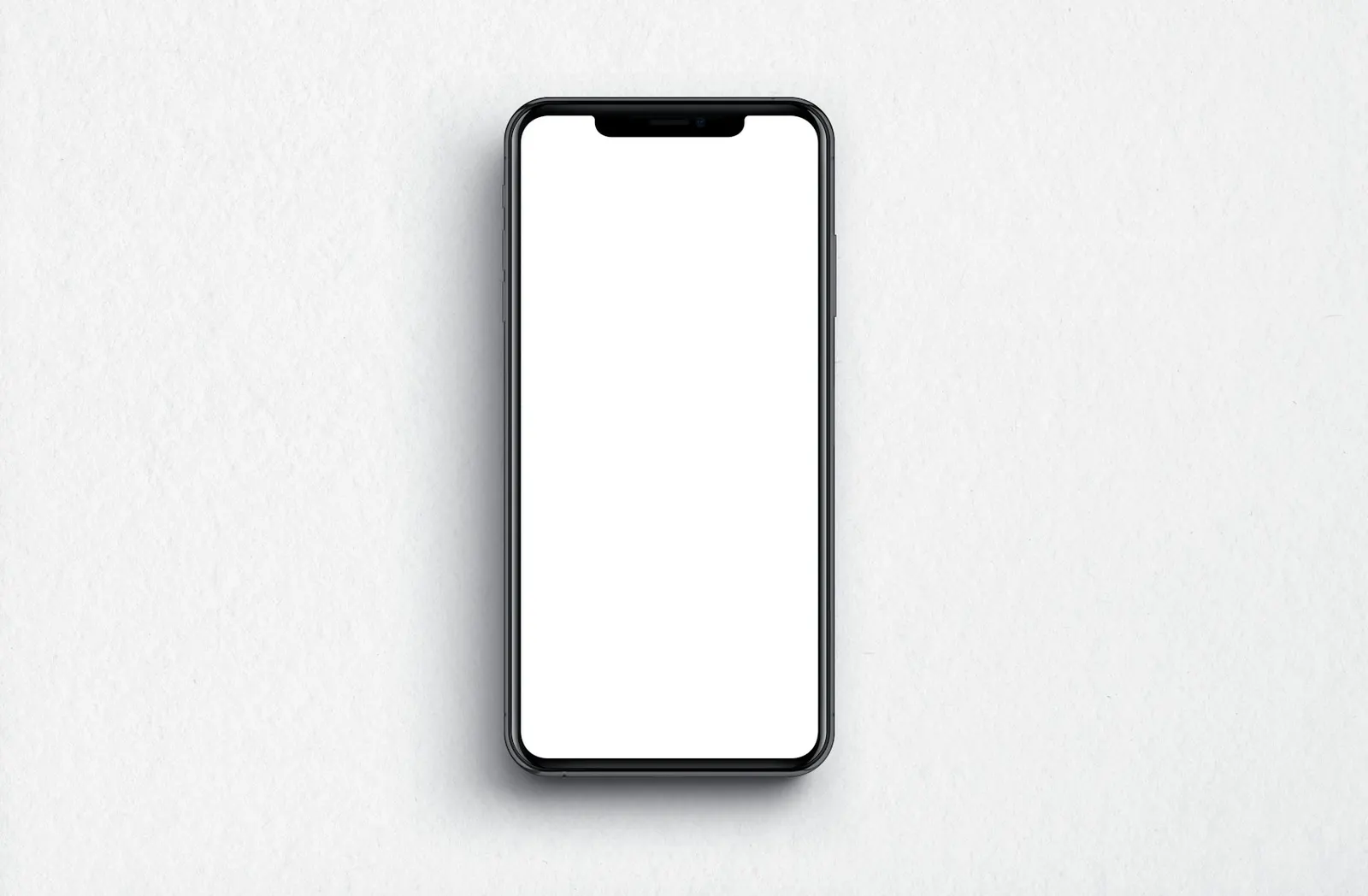 A black smartphone with a blank white screen lying on a light grey surface.