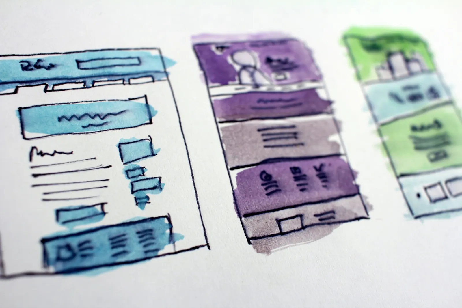 Three hand-drawn, watercolour sketches of website page layouts on white paper.