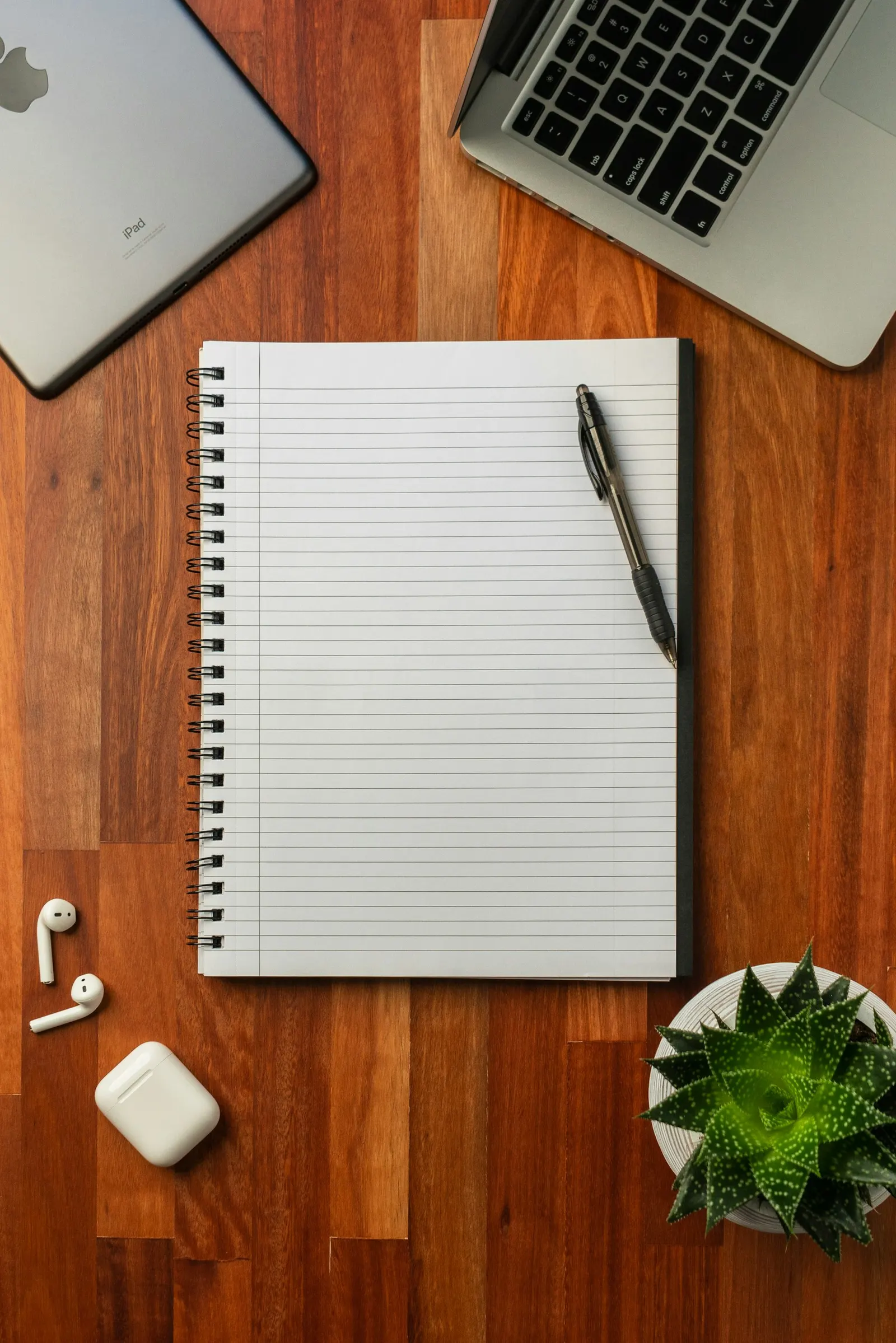 An open notebook with a pen lying on a wooden table.