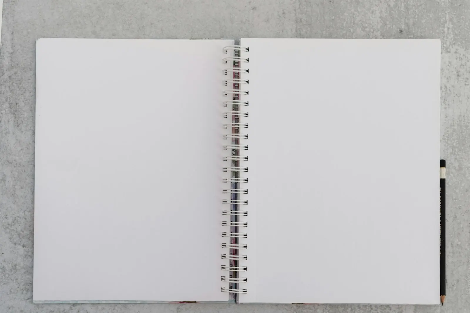 An open blank notebook lying on a grey concrete surface.