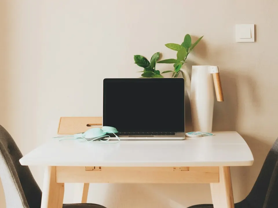 A tidy wooden desk with a laptop in soft, warm light