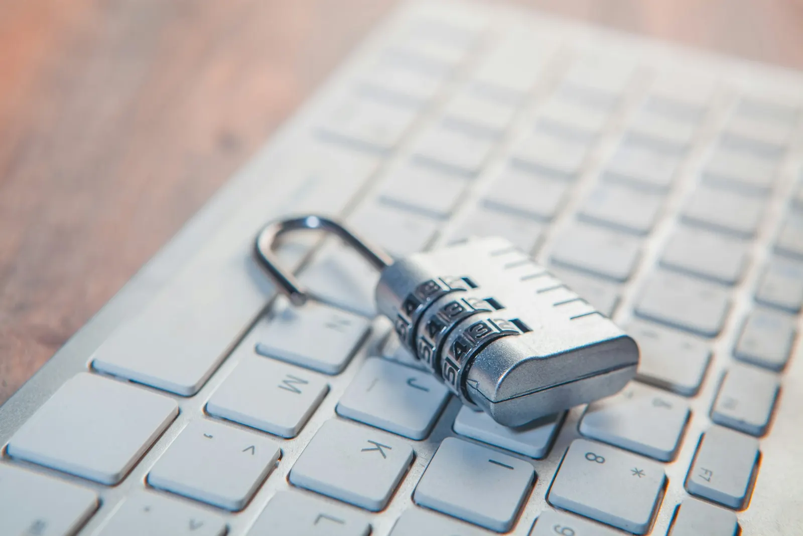 An open combination padlock lying on a white computer keyboard.